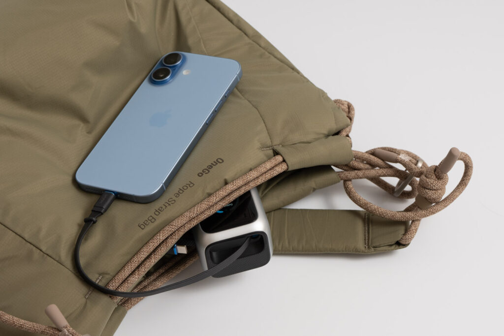Anker Power Bank (25000mAh, Built-In & 巻取り式USB-Cケーブル)をバッグに収納しながらiPhone 17を充電している様子