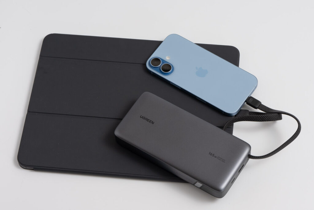 UGREEN 25,000mAhモバイルバッテリー 165Wの内蔵USB-CケーブルでiPhone 17と13インチiPad Proを同時充電している様子
