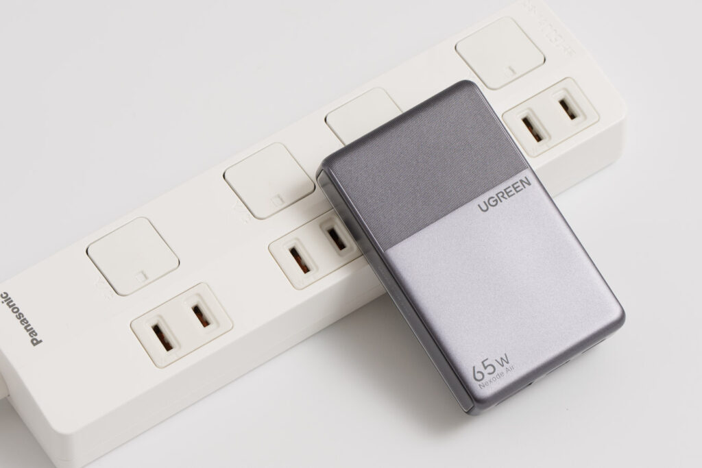 UGREEN Nexode Air 65W Slimを電源タップに接続している様子(隣の挿し込み口に本体がかかる)