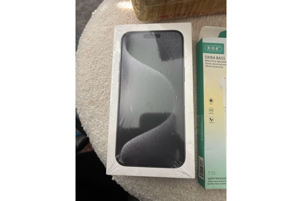 注文していないのに届いたとされる、封をしたままのiPhone 15 Pro Maxの箱と安価な有線イヤフォンの箱(Reddit投稿者の写真)