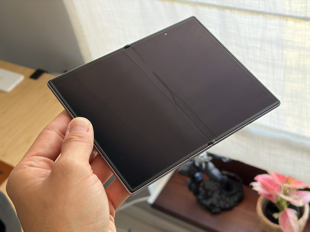 数日使用したGalaxy Z Fold8を開いて手に持ち、消灯した内側画面の中央に縦の折り目が見えている写真