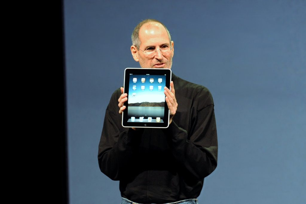 2010年1月27日の発表イベントで初代iPadを掲げるスティーブ・ジョブズ氏